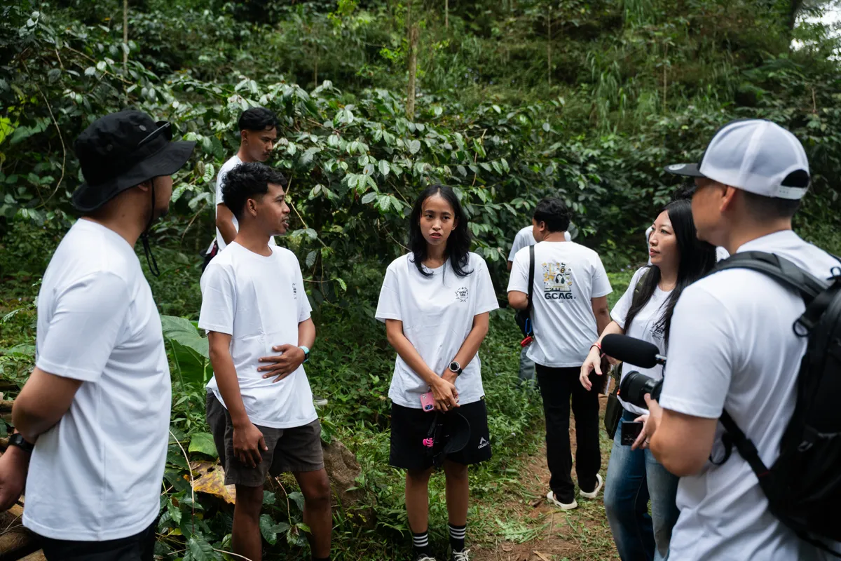 GCAG participants exchanging ideas among coffee plants during a farm visit.
